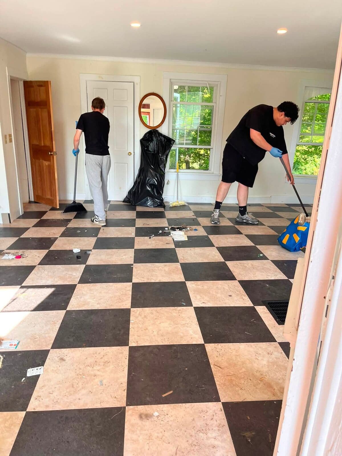 Two crew members mopping a checkerboard kitchen