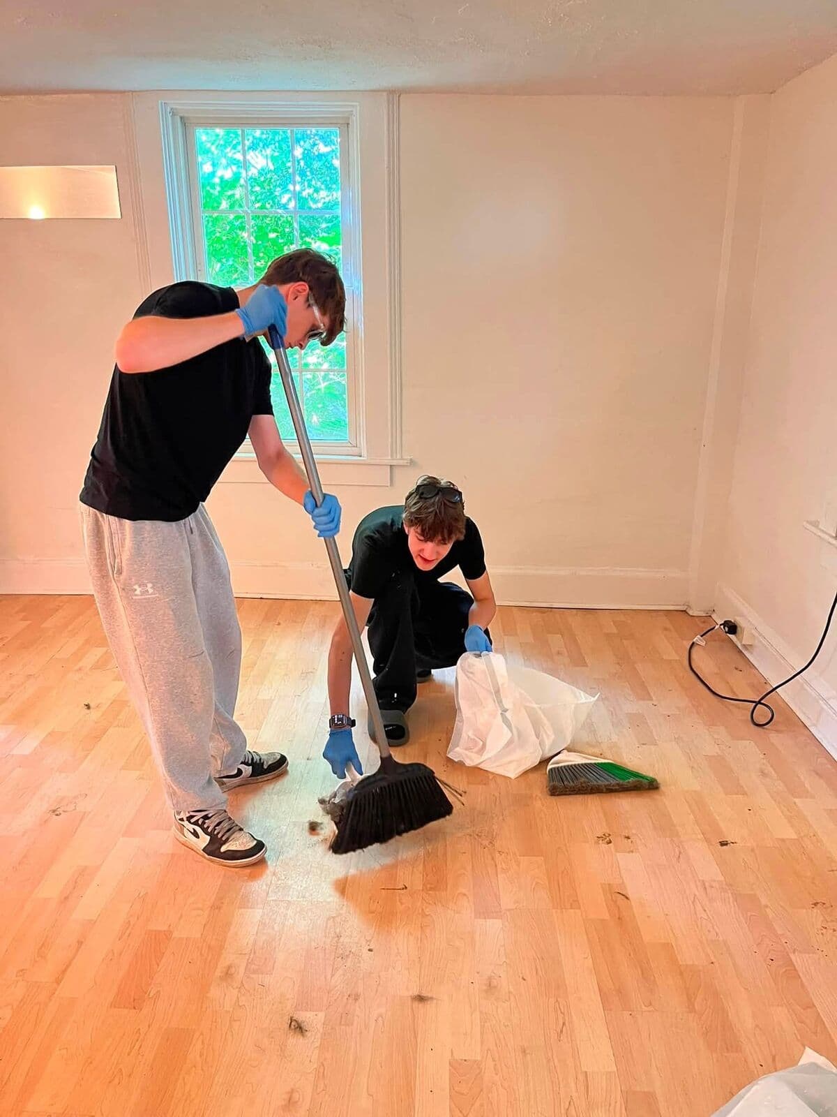 Two crew members sweeping up after a renovation