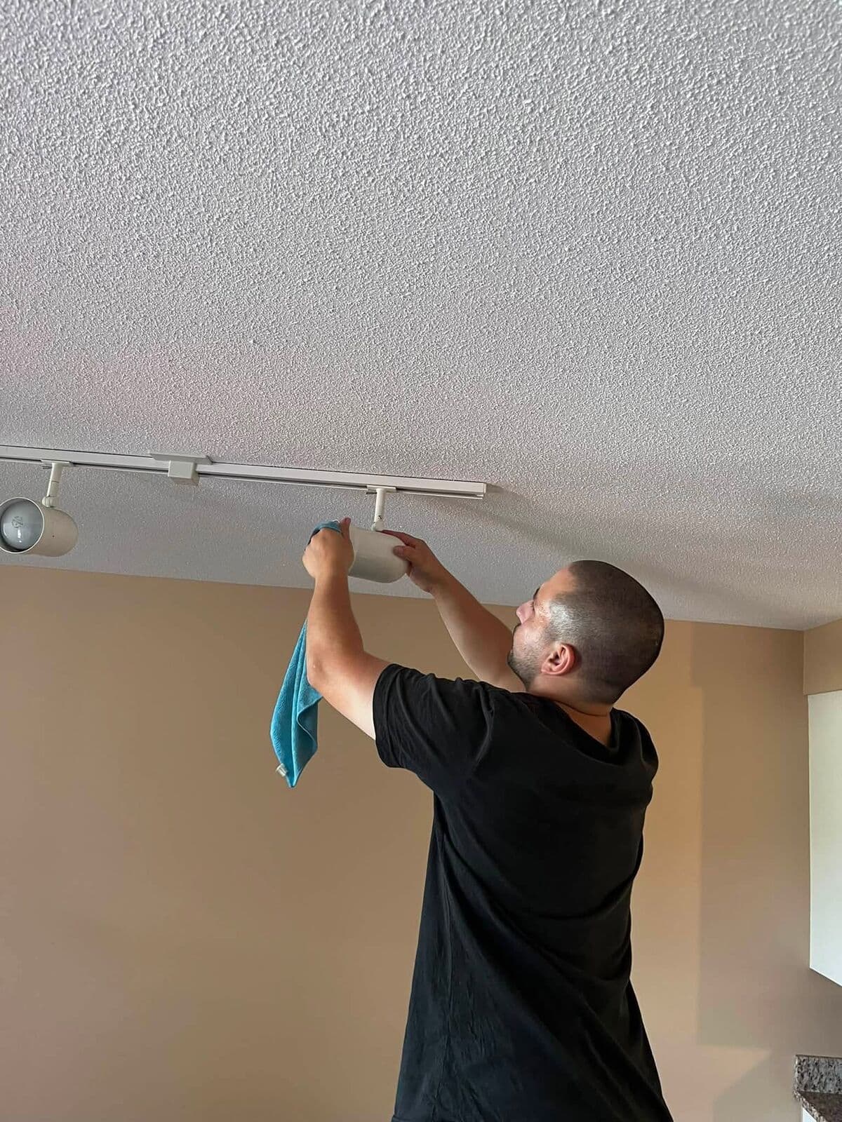 Crew member wiping a ceiling light fixture