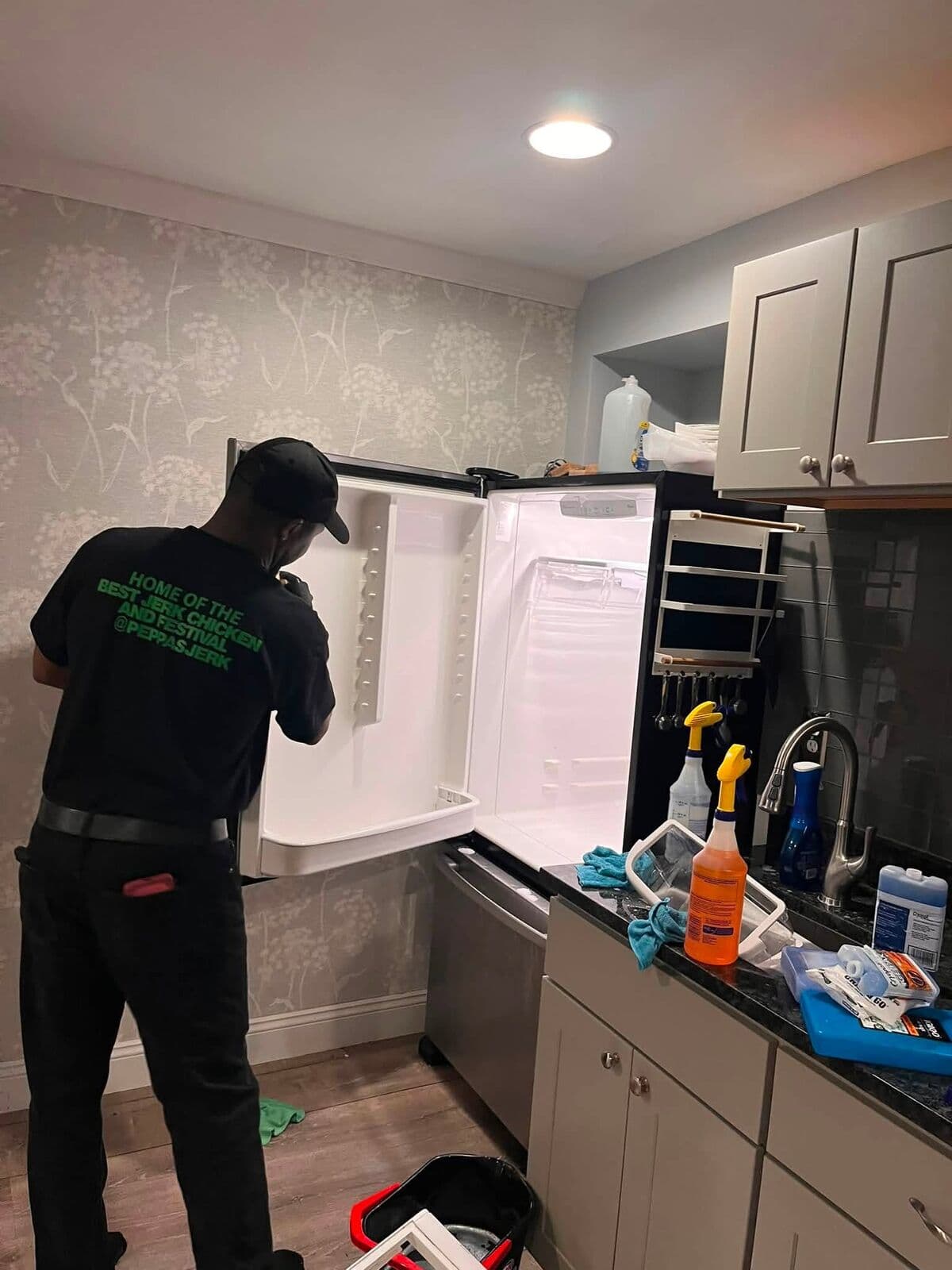 Crew member cleaning a fridge in a modern kitchen