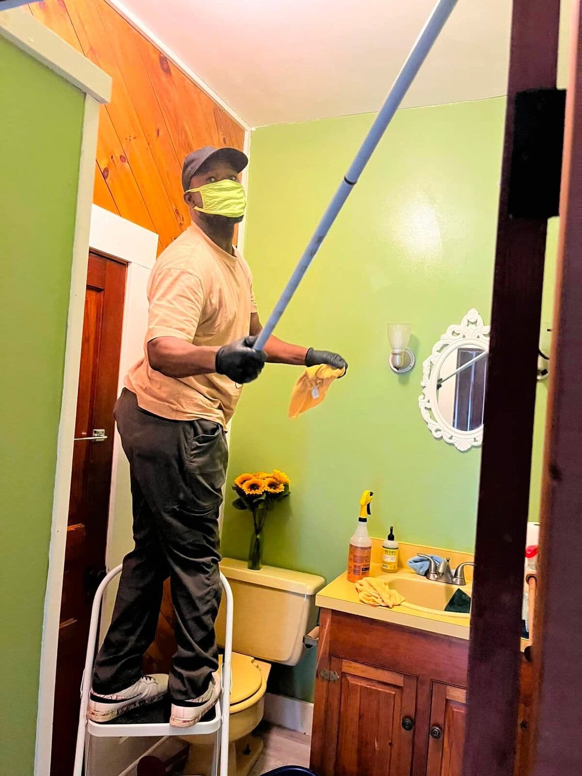 Crew member dusting high corners with an extension pole